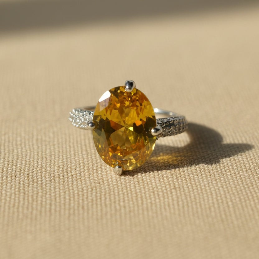 SVORA Ethereal Yellow Sapphire Solitaire Ring with oval-cut yellow stone, pavé shoulders, and rhodium-plated stainless steel band.