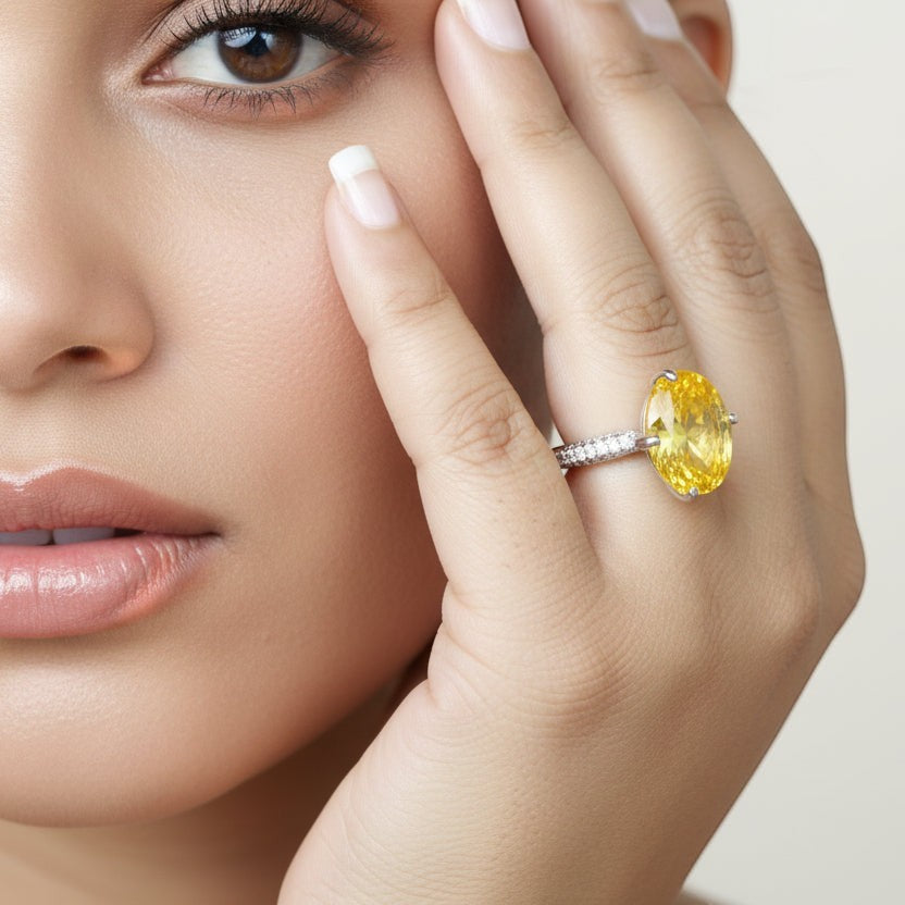 SVORA Ethereal Yellow Sapphire Solitaire Ring with oval-cut yellow stone and pavé shoulders on a rhodium-plated stainless steel band.